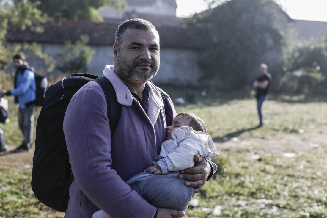 Syrian refugee Yasser Hussein carries his three-month-old son towards a registration centre for refugees in Preševo, southern Serbia, on October 5, 2015. Photo credit: Sam Tarling / Oxfam